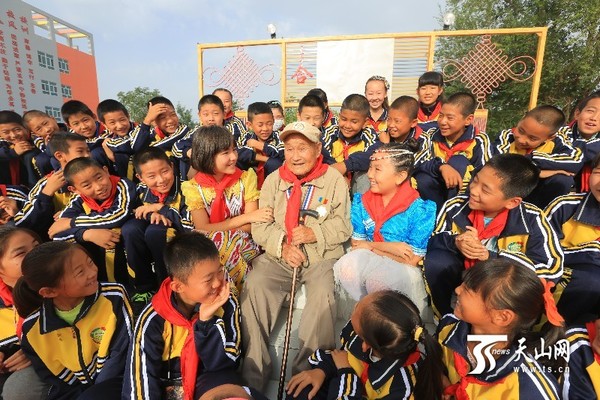 学生们正围在老兵牛维刚身边，认真地听着老人讲述当年的战火青春和坎坷经历。