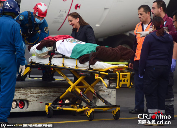 　　当地时间2015年9月18日，墨西哥墨西哥城，在埃及军警错杀墨西哥游客事件中幸存的墨西哥游客乘坐总统专机抵达，身上盖着墨西哥国旗被送往医院。图片来源：CFP