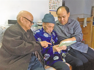 金树林老人（中）与儿孙一起回忆旧时照片。记者 卢婉娉 摄