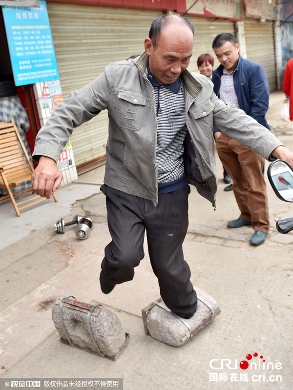 2015年10月29日，成都5旬大叔每天挂百斤石锁散步练成肌肉男。 挑战者没走几步就败下阵来。图片来源：张磊/视觉中国