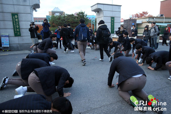 当地时间2015年11月12日，韩国高考当天开考，学弟学妹跪地鼓励参加考试的学长。图片来源：视觉中国