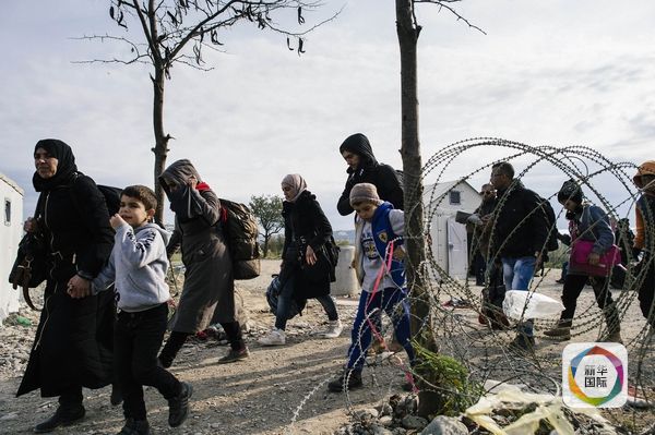 11月15日,难民通过希腊和马其顿边界。(图片来源:新华/法新)