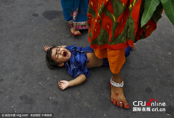 当地时间2015年11月17日，印度加尔各答，印度教徒祭拜日神，庆祝太阳神节。一名印度教妇女跨过一名儿童为其祈福。图片来源:Reuters/视觉中国