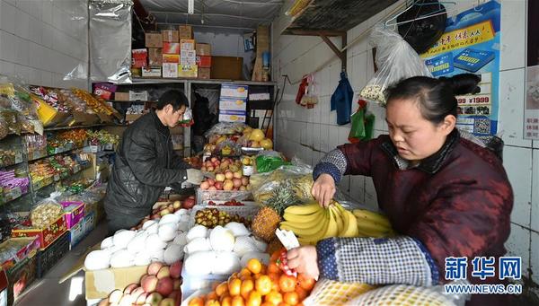 王亮明（左）一家人在店里整理水果（12月2日摄）。 新华社发（曹阳摄）