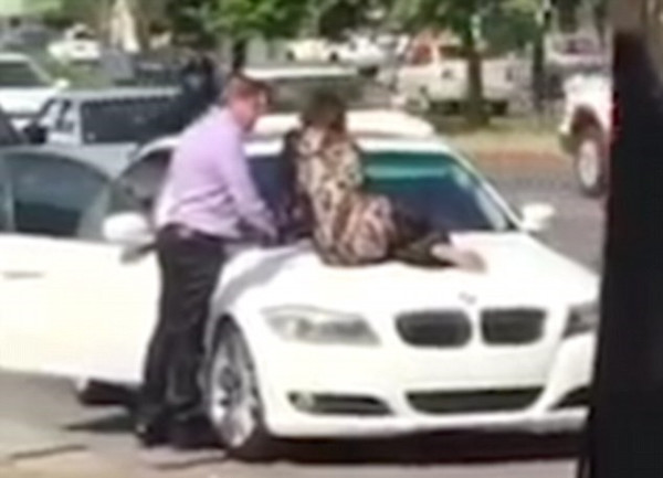 女子坐在宝马车头（视频截图）