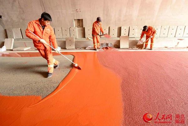 工人在麻竹高速保康黄堡段风儿垭隧道铺设警示线。