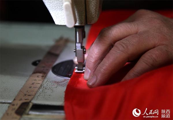 呼延振元裁剪好缎面,唐春玉负责在缝纫机上缝好,为了能按照尺寸裁剪好,唐春玉专门给缝纫机上贴上尺子。杜旭涛 摄