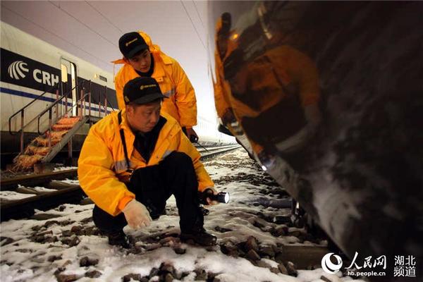 “动车保姆”在雪夜天气下检查动车组走行部设备状况。（许辉 摄）