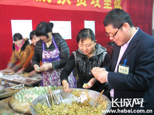 　　卷掌村党支部书记李玉法和村民一起包饺子。