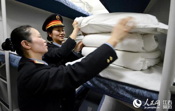 在卧铺车厢，徐洪燕和列车员整理卧具。