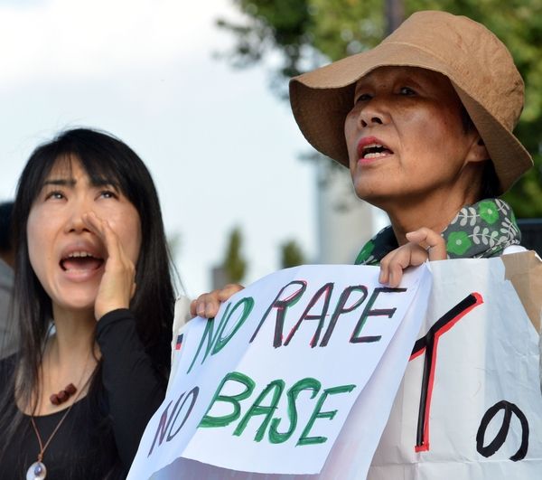 　　2012年10月20日，两名日本市民在日本东京的首相官邸前手举标语抗议驻冲绳美军。（图片来源：新华/法新）