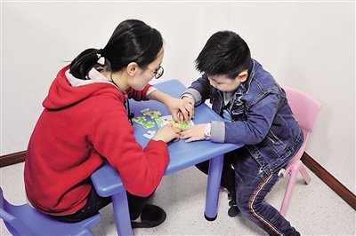 医护人员陪小豪做拼图游戏。
