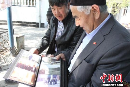 “喀什噶尔村”维吾尔协会会长乌璐耶夫&middot;哈不拉江翻看他在中国参观的影集，他常去中国，曾经走过中国许多省市，见过大世面。　陶拴科 摄