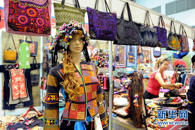 11月3日，在老挝首都万象，一名参展商向顾客推销老挝传统手工服饰。