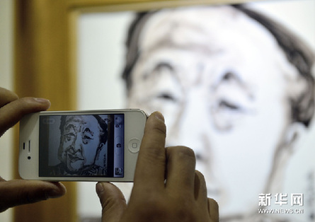 12月9日，一位观众拍摄罗皓的瓷板画《作家莫言》。新华网图片 于点 摄