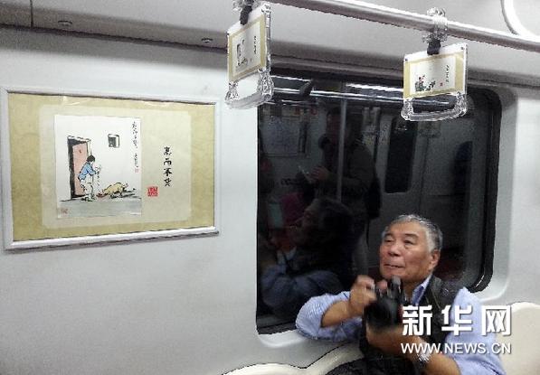11月7日，一名乘客在上海地铁11号线1109号列车上拍摄车厢里的丰子恺漫画。新华网图片 黄炎 摄