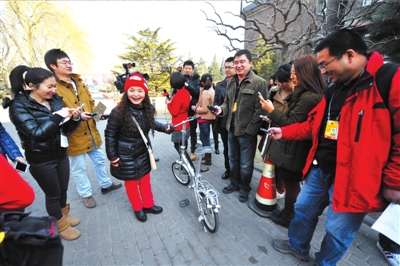 吴碧霞代表骑着自行车报到。本报记者张斌摄/视频