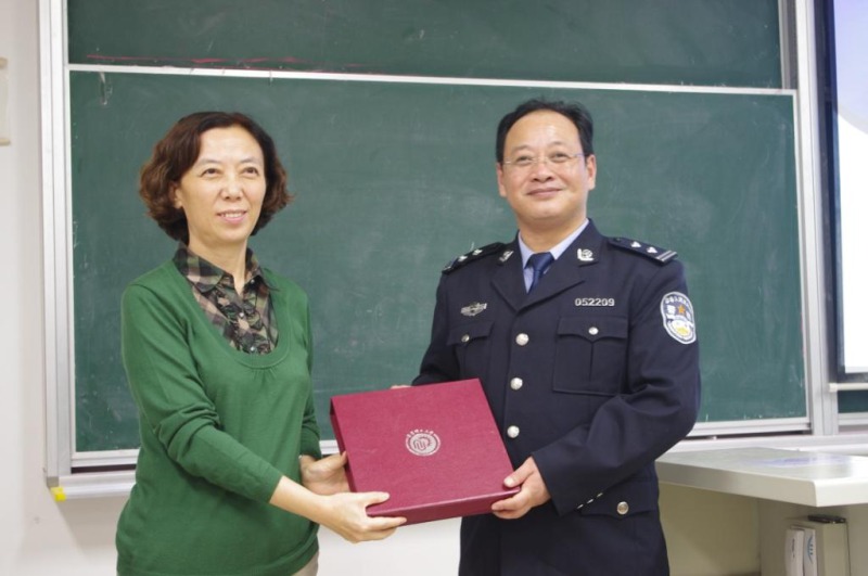 图片说明：副院长纪晓岚教授向慕守文警官赠送学校纪念品