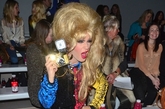 伦敦2012秋冬时装周Ashish专场，名媛Jodie Harsh顶着夸张金色蓬蓬头坐在场内看秀，手拿复古相机咔嚓闪拍个不停。
