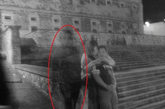 街头鬼影：一对夫妇坐在台阶上，一个奇怪的影子在旁边看着他们。怀疑者解释说，这个模糊的人影似乎是曝光时间过长造成的。可能是拍摄照片时，一位路人走过时造成的。