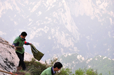 两名环卫工在华山东峰下捡拾塑料袋等垃圾。