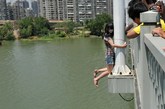 7月24日中午，武汉，一名年轻女子爬上汉阳知音桥的灯杆，路人苦劝一个多小时无果，直到其男友下跪认错，她才爬回桥面。