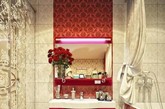地砖与浴缸贴面采用的是浓烈的赤红色，而橱柜背景也采用了与浴缸贴面同样的瓷砖，一直从地面延伸至屋顶，其他部分的的背景墙瓷砖，选择了米白色雕花瓷砖，颇具古韵味。红色的挂壁式橱柜是这件卫浴间的现代元素，单一的红色加上白色的台面，简约时尚，挂壁的设计，十分节省空间，勿忘在收纳台上放上一瓶插花，主人为其配上了最经典的玫瑰花，卫浴间时不时透着的浪漫气质。
