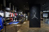 店铺入口处和中央的两个展台分别陈列 Nike Basketball 和 Jordan Brand 当季精品，同时搭配巨型荧幕播放宣传片。地板则特别设计为老式篮球馆的人字形拼花，并描上球场的界线。球衣模特以手抓篮球或是投篮姿势被放立在特别位置，角度对应高处特设的篮筐，相信爱篮球的同学走进店内定会激动得血脉喷张吧。（实习编辑：容少晖）