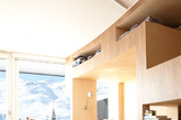 这间公寓位于法国一个滑雪度假胜地，由h2o Architects设计, 位于法国滑雪胜地Menuires。原来的公寓布局有三个卧室，一个浴室，没有公共空间。新的改建在55平方米内安置了8张床，两个浴室，一个大的公共空间。设计师最大限度的利用了空间，并设计出了为空间定制的家具，这系列家具神奇的减小了公寓的狭窄感。木家具沿一条大曲线布局，将所有的功能装进去，并留出了纯白宽敞的公共空间和看向山的视野。大的木家具里面有睡眠，储存，休息，阅读等等功能，拉上窗帘就能睡觉。整体空间用材主要是木材，采用的材料是美国胡桃木胶合板和桦木胶合板。