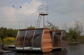 APEcolodges 在荷兰一家度假村的湖面上完成了这个有趣的空间。它像双体船一样有两厢，其中一厢是小厨房和浴室，另一厢是供休息的床铺。整座木屋选用较轻的铝制框架，用红雪松木和钢化玻璃完成。建筑师想要通过这样简单的设计，让使用者安静地去体验自然。（实习编辑：李黎星）