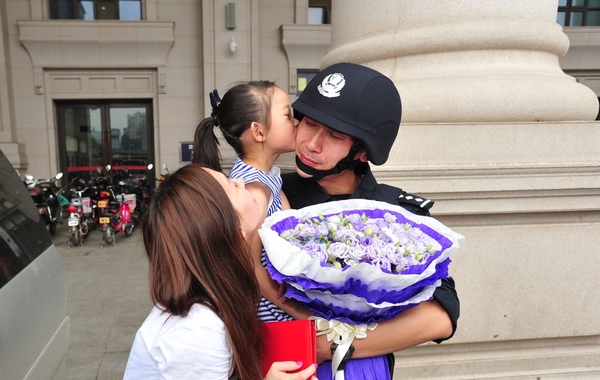 图为:妻女看望在汉口火车站广场执勤的特警刘尚东,女儿扑进他的怀里亲