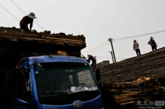 垃圾村附近一个堆积木材的场所，几名女工在将木板装上车。（实习编辑：石君兰）