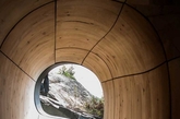 在加拿大安大略省的乔治亚湾地区，这个如同雕塑般的「Grotto」桑拿房栖息在一个私人岛屿的海湾边 ，由当地设计工作室PARTISANS设计和构建。温馨的桑拿浴室内部空间被设想为一个可通风对流的「洞穴」，并以蜿蜒的形式大胆呈现出来，大大的玻璃窗可欣赏到整个海湾的风景，而位于屋顶平面上的天空带来自然采光 。整个建筑大部分皆预制而成，再运输到此安装。（实习编辑：江冬妮）