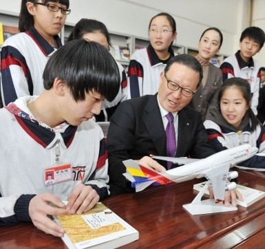 图释：韩亚航空尹永斗社长（前排从左第2）赠送图书之后拿出一个飞机模型，给学生讲解了飞机的飞行原理