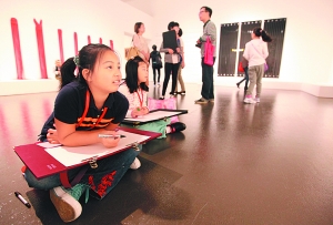 　　前来参观的少年儿童席地而坐，进行绘画临摹。刘歆 图