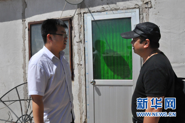 8月下旬，在北京市大兴区庞各庄镇王场村，大学生村官陈墨（左）在曾经住过的板房前向记者讲述他的创业故事。新华网记者 姜春媛摄