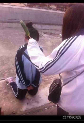 网上流传的照片显示,一名女生拿着黄瓜正教训跪在地上的女生.
