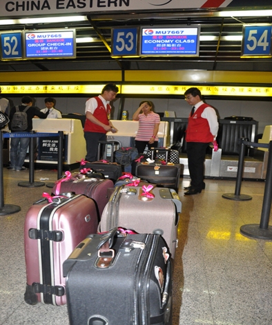青年突击队员协助旅客在托运行李上栓挂彩带以区分航班 (作者单位