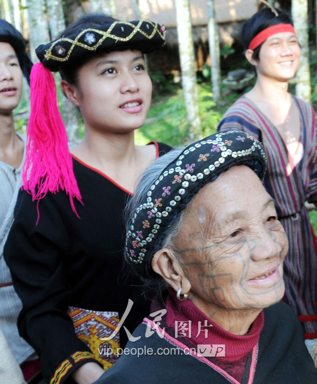 在海南省保亭黎族苗族自治县一景区，一位黎族女子和一位有文身的阿婆站在一起。曾是黎女的生死成人礼，古老而独特的文身之美，得不到现代年轻黎女青睐。 （2011年12月3日摄）