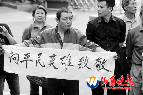 一位自发送别吴斌的市民在马路边打出致敬的横幅