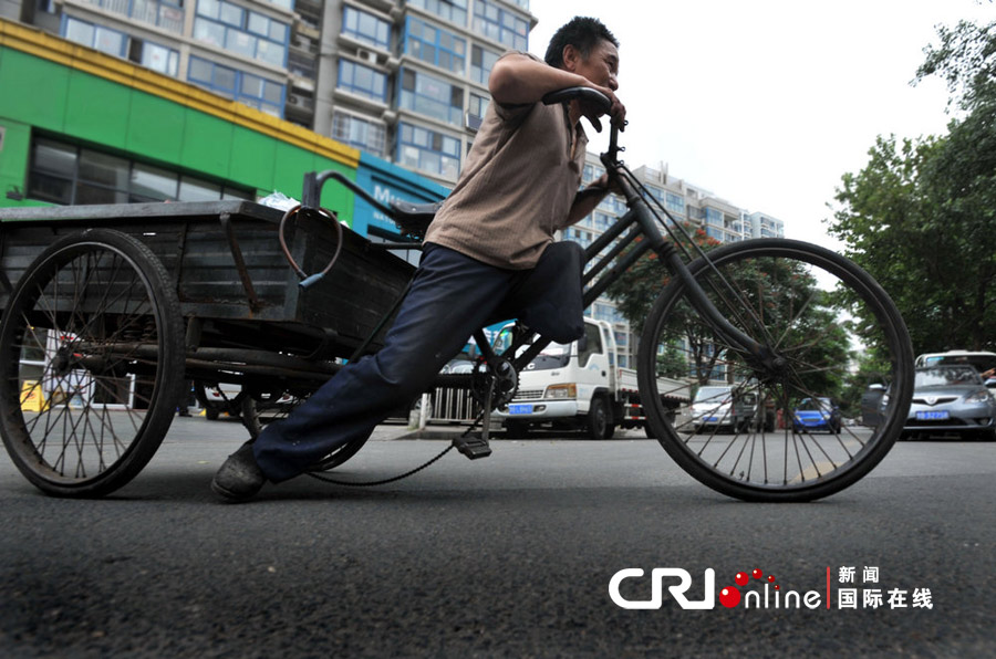 　　2012年6月25日，青岛，老李靠一条腿奋力蹬地前行。 图片来源：CFP