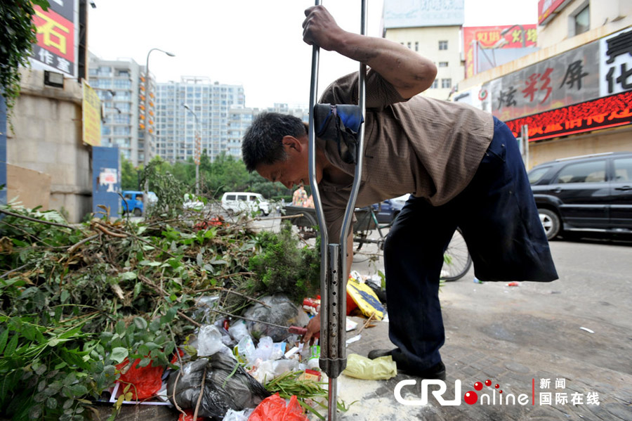 独腿“破烂王”李传声撑着拐杖在路边捡拾能换钱的废品。图片来源：CFP