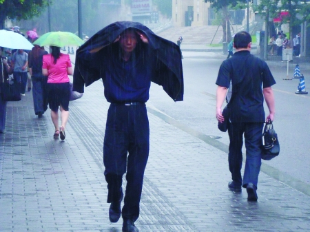 "黑"衣人  渝中区大礼堂附近,一位中年男子用外衣遮雨.