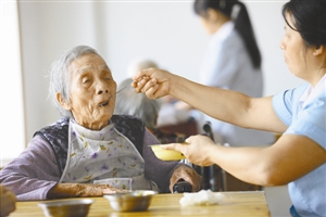 养老院工作人员在照顾老人饮食起居.(资料图片)