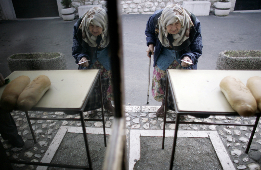 南斯拉夫萨拉热窝,一名波斯尼亚老妇从桌子上拿免费食物摄于2008年