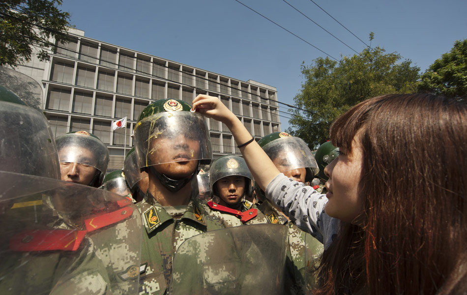 一個女孩為武警擦去頭盔上的雞蛋殘液