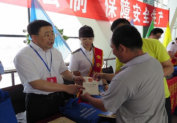 沈阳铁路监管局局长高文(左一)在沈阳北站向旅客发放安全法律法规书籍