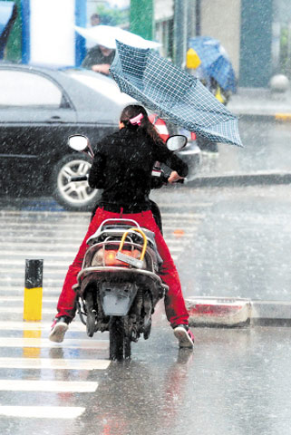 29日上午,長沙突降暴雨,市民騎電動車橫過馬路(圖片來源:長沙晚報)